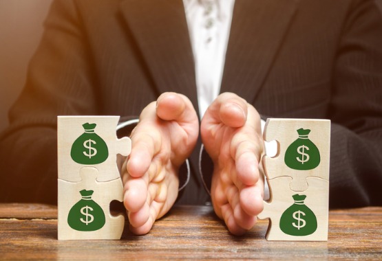 man in suit separating wooden blocks with pictures of money bags on them