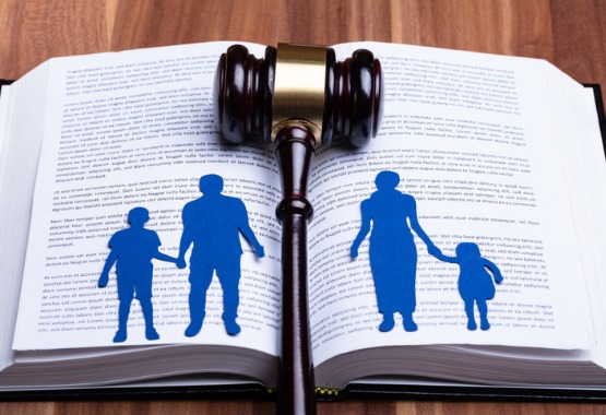 An open book with a cutout of a family separated by a gavel, representing Family Law in Peoria IL