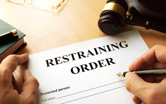 A person fills out paperwork after learning How to Obtain a Restraining Order